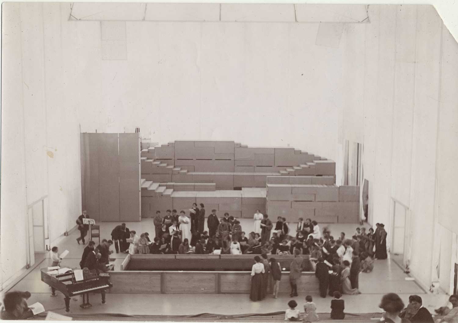 Foto, schwarz-weiß, innen: Ungefähr vierzig Personen stehen und sitzen in Grüppchen im Raum verteilt.