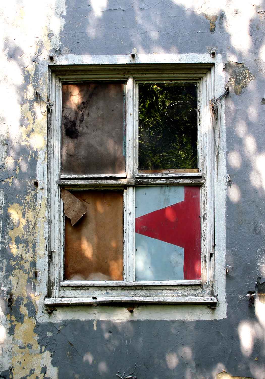 Foto, farbig, außen: Blick auf ein verwittertes Fenster.