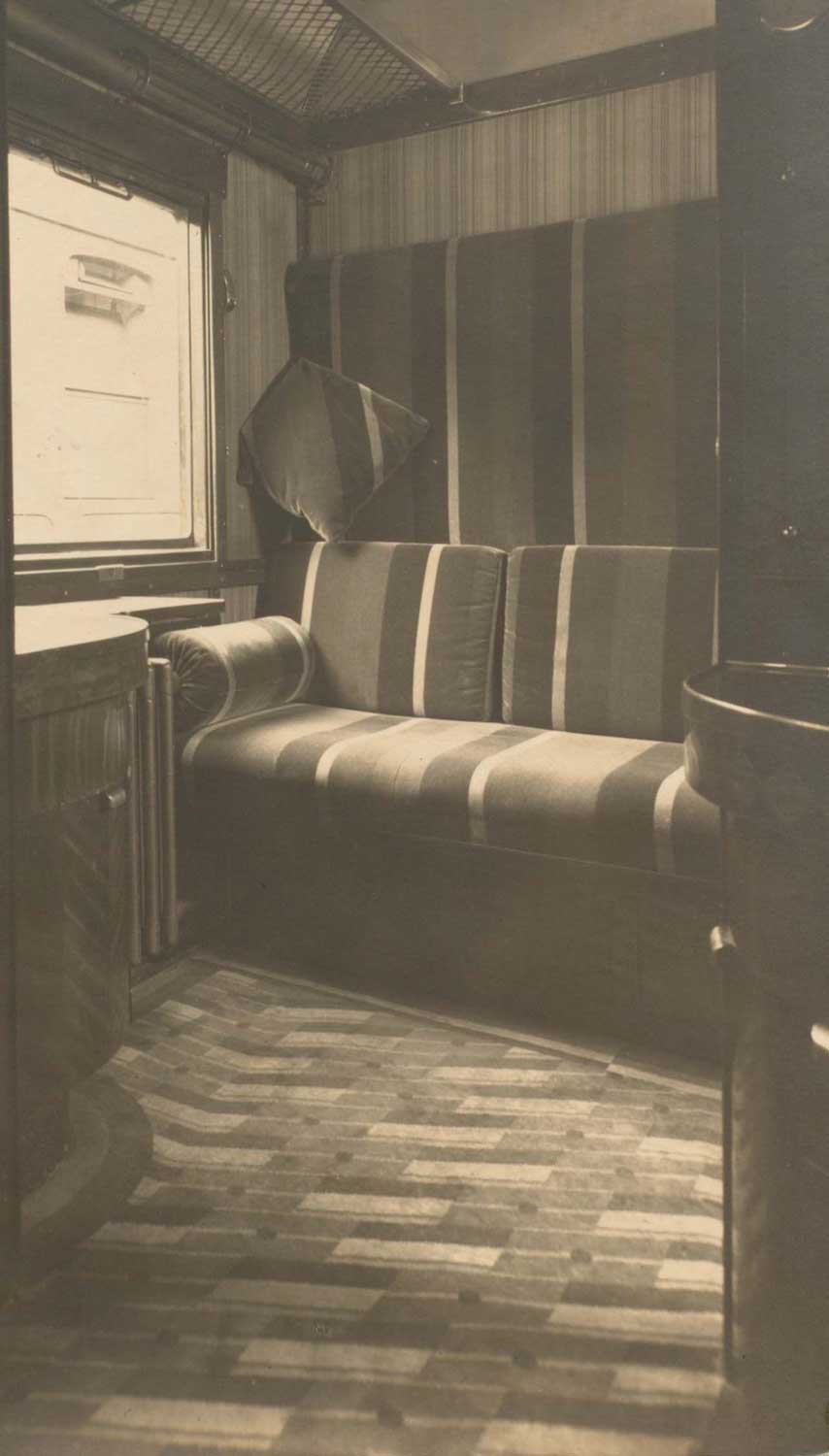 Foto, schwarz-weiß, innen: Sitzbank mit Stoffbezug aus breiten und schmalen Streifen.