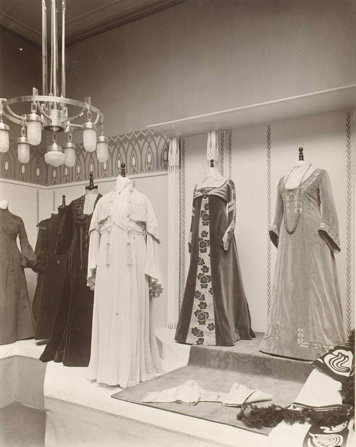 Foto, schwarz-weiß: Fünf lange Damenkleider in einer Schaufenster-Auslage.